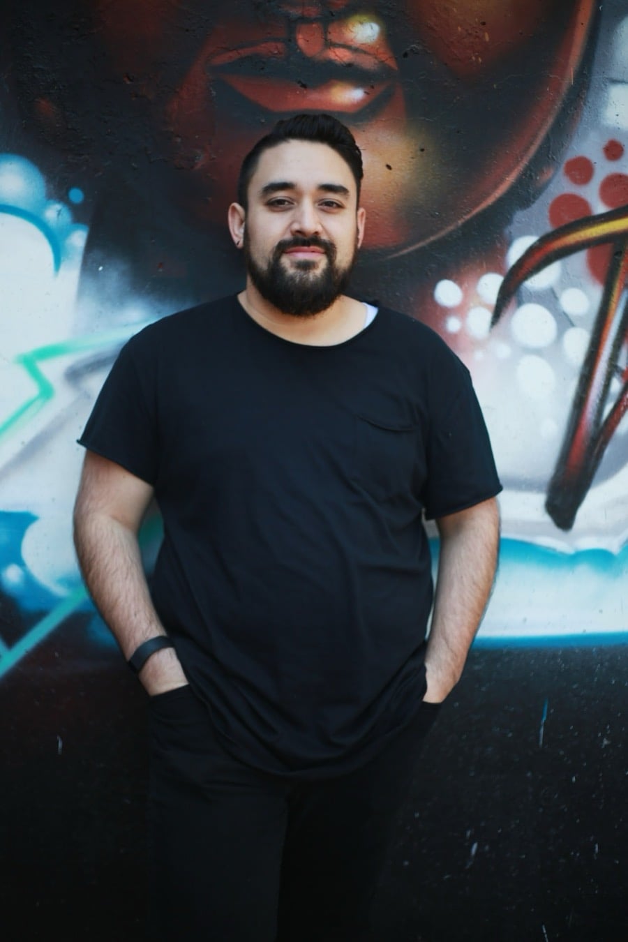 Ben McDonald smiling in front of a graffiti wall